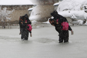 Evinin önünde biriken su nedeniyle çocuklarını sırtında taşıyor